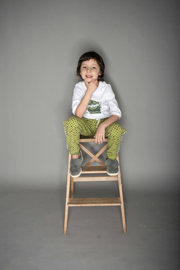 Child sitting on a wooden stool against a gray background